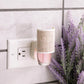 Mellow Monkey Linen WallScents fragrance warmer plugged into a wall outlet next to a lavender plant.