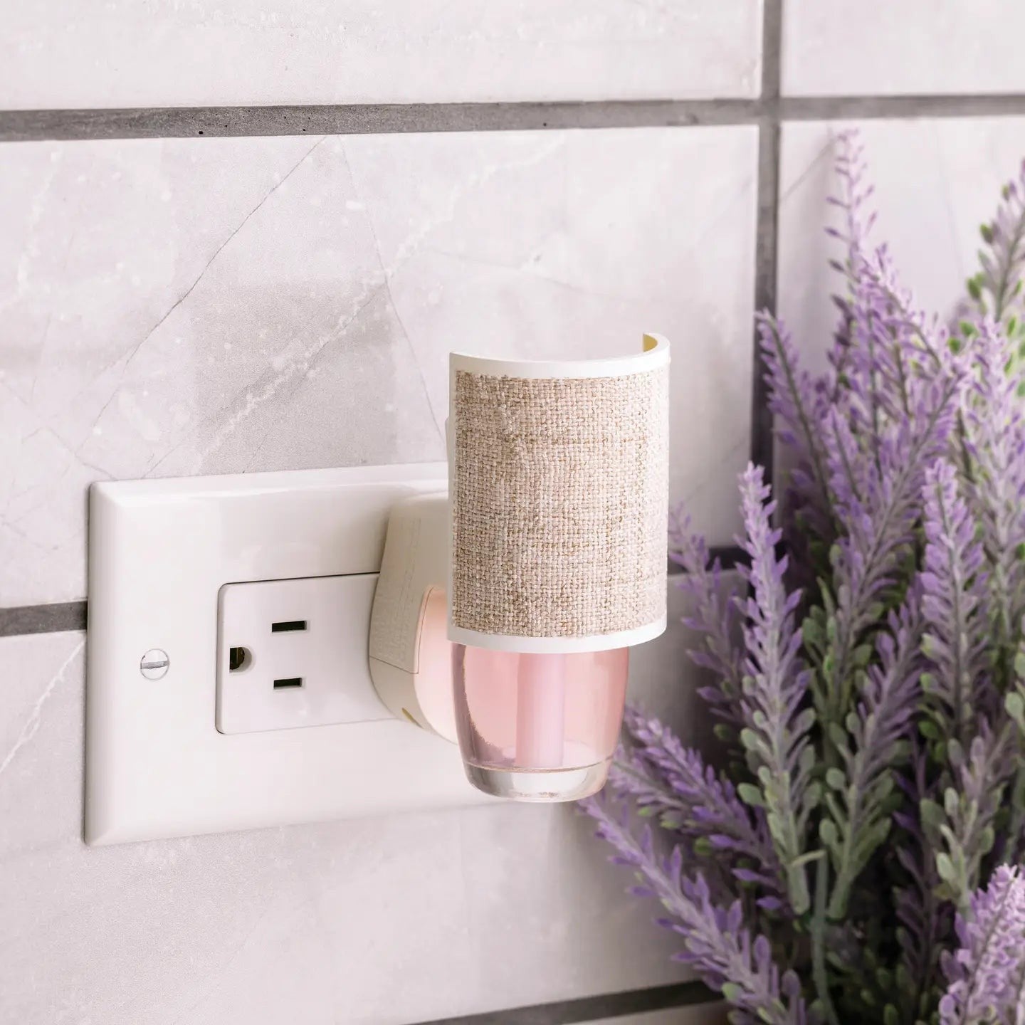 Mellow Monkey Linen WallScents fragrance warmer plugged into a wall outlet next to a lavender plant.