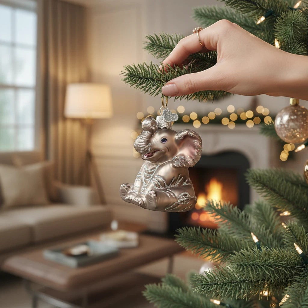Mellow Monkey Little Elephant Old World Christmas blown glass ornament, silver with glitter accents, hanging on a tree.