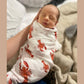 Mellow Monkey muslin swaddle blanket with red lobster print wrapped around a sleeping newborn baby