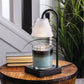 Mellow Monkey Lumiere candle warmer lamp with black base and fluted glass shade warming a jar candle on a wood table