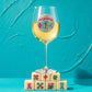 Mellow Monkey 19 oz stemmed wine glass featuring a jeweled Mahjong tile emblem, resting on a stack of Mahjong tiles.