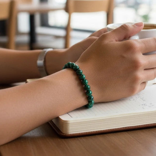 Mellow Monkey malachite synthetic stone beaded bracelet on a person holding a coffee cup at a desk.