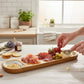 Mellow Monkey 16-inch sectioned mango wood tray filled with charcuterie, grapes, and cheese on a kitchen counter.