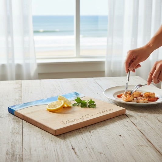 Mellow Monkey maple wood cheese board with blue resin ocean detail, engraved with Taste of Connecticut on a table.