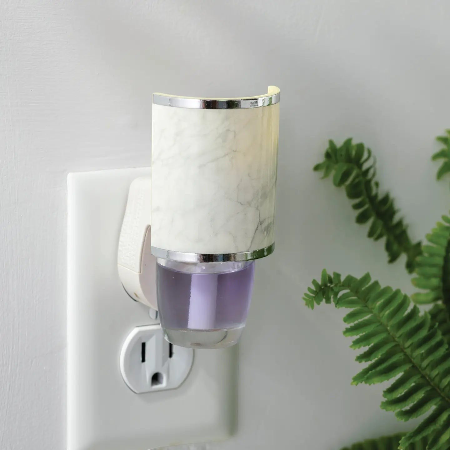 Mellow Monkey Marble WallScents fragrance warmer plugged into a wall outlet with a purple oil refill.