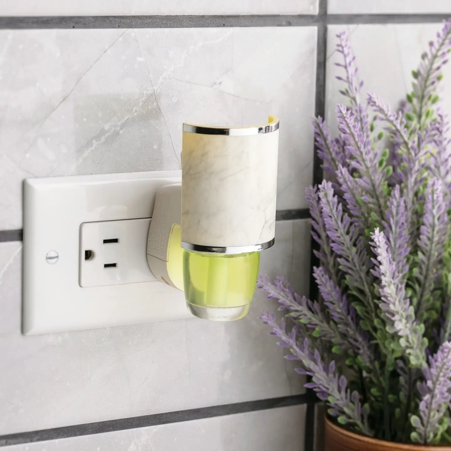 Mellow Monkey marble fragrance warmer plugged into a wall outlet with a green oil refill, set against tiled wall.