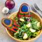 Mellow Monkey Marrakesh Salad Hands, ergonomic hand-shaped wooden salad servers with vibrant blue, orange, and green wood grain pattern.