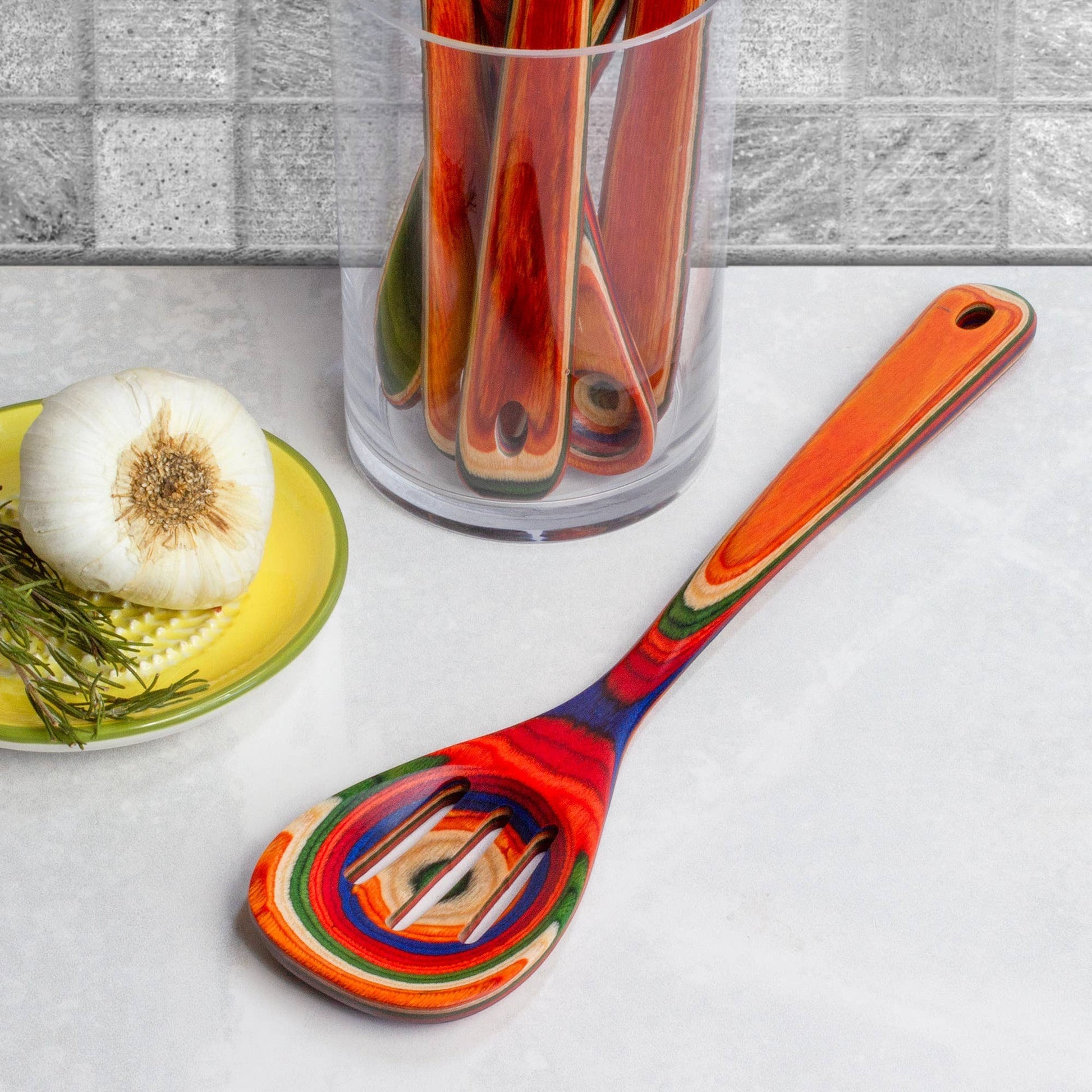 Mellow Monkey Marrakesh Collection wooden slotted spoon with vibrant red, orange, blue, and green swirls. 12.5-in.