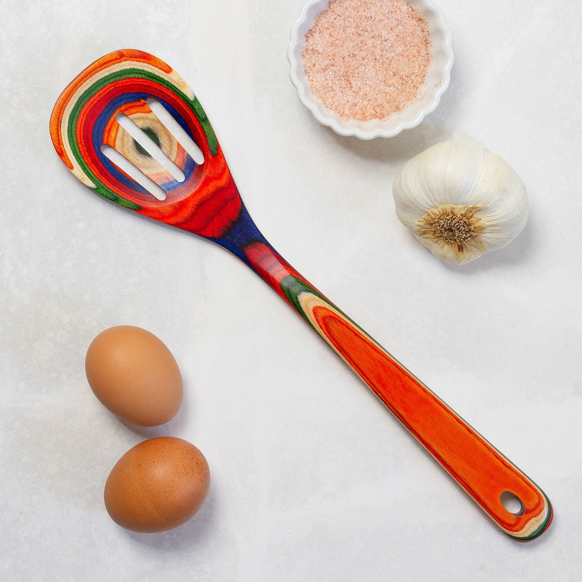 Mellow Monkey Marrakesh Collection wooden slotted spoon with colorful swirls of red, blue, green, and orange. 12.5-in.