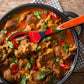 Mellow Monkey Marrakesh Collection wooden slotted spoon with colorful swirl design, 12-1/2-in, stirring a pot of lamb curry.