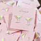 Mellow Monkey martini cocktail stud earrings with olive garnish on pink display cards