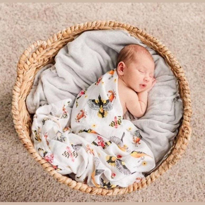 Mellow Monkey Maryland themed muslin baby swaddle blanket featuring state flag, crab, and oriole print on a newborn.