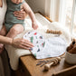 Mellow Monkey 2-in-1 bamboo and cotton burp cloth and bib featuring Massachusetts-themed icons on a baby changing table