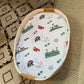 Mellow Monkey Massachusetts themed muslin baby swaddle blanket with state icons in a rope basket on a patterned rug.