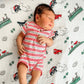 Newborn baby sleeping on a Mellow Monkey Massachusetts themed muslin swaddle blanket with state icons and symbols.