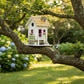 Mellow Monkey May Cottage birdhouse with pink door, flower boxes, and stone accents, perched on a tree branch.