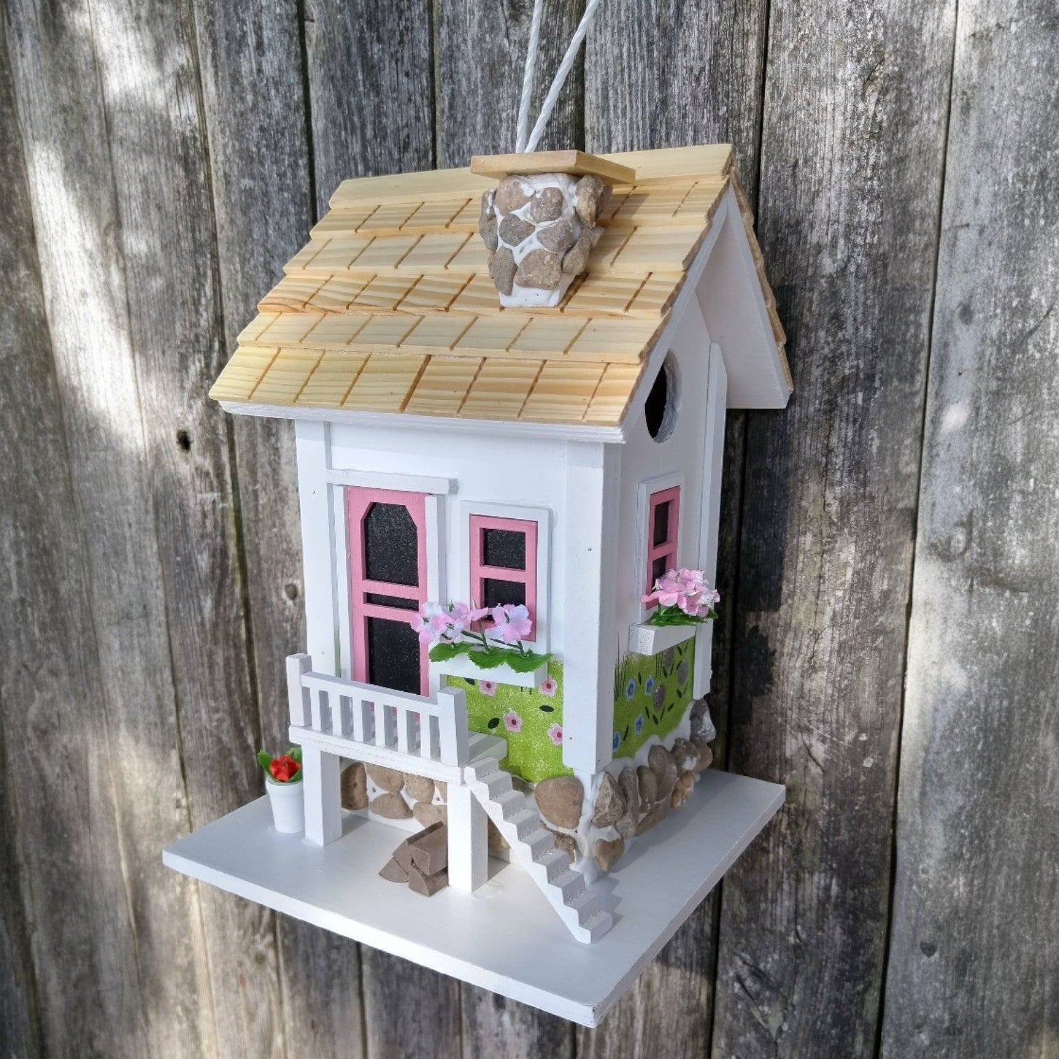 Mellow Monkey May Cottage birdhouse with white exterior, pink door and windows, flower boxes, and stone accents.