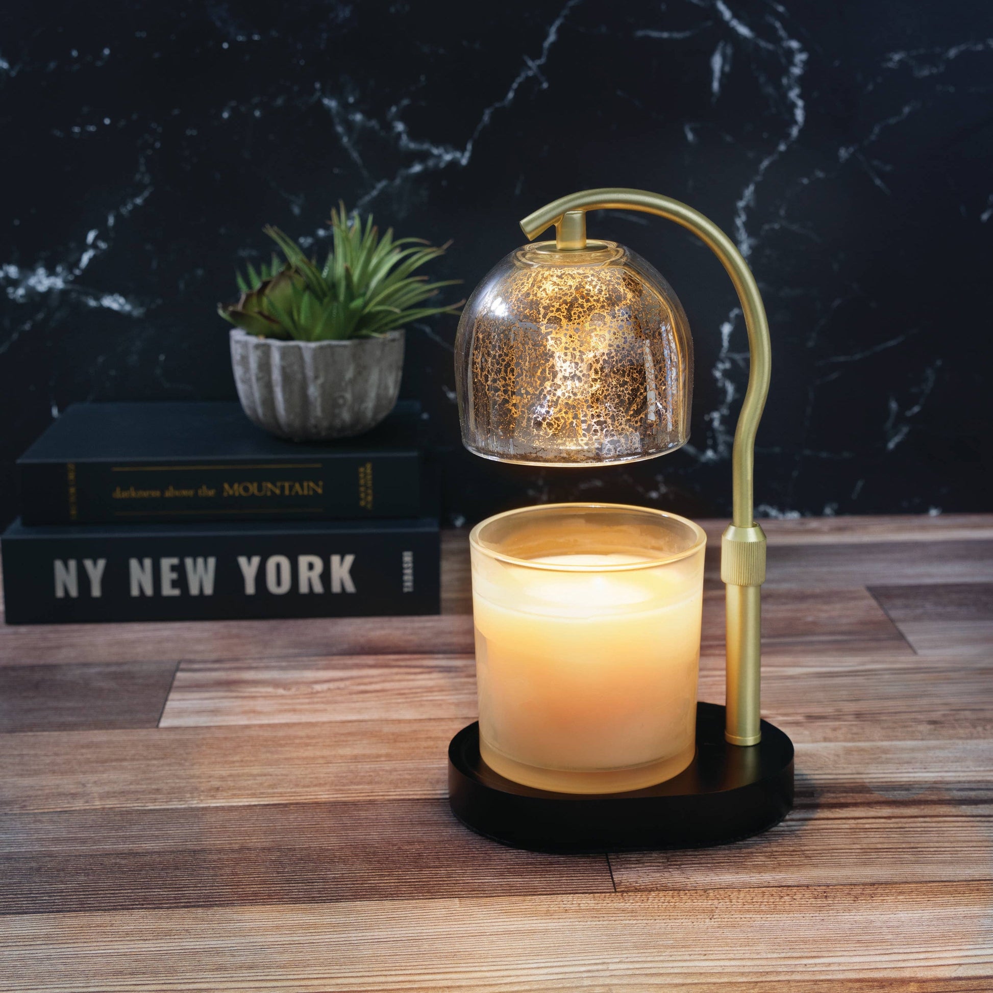 Mellow Monkey mercury glass candle warmer lamp with gold shade, adjustable stem, and black base on a wooden table.
