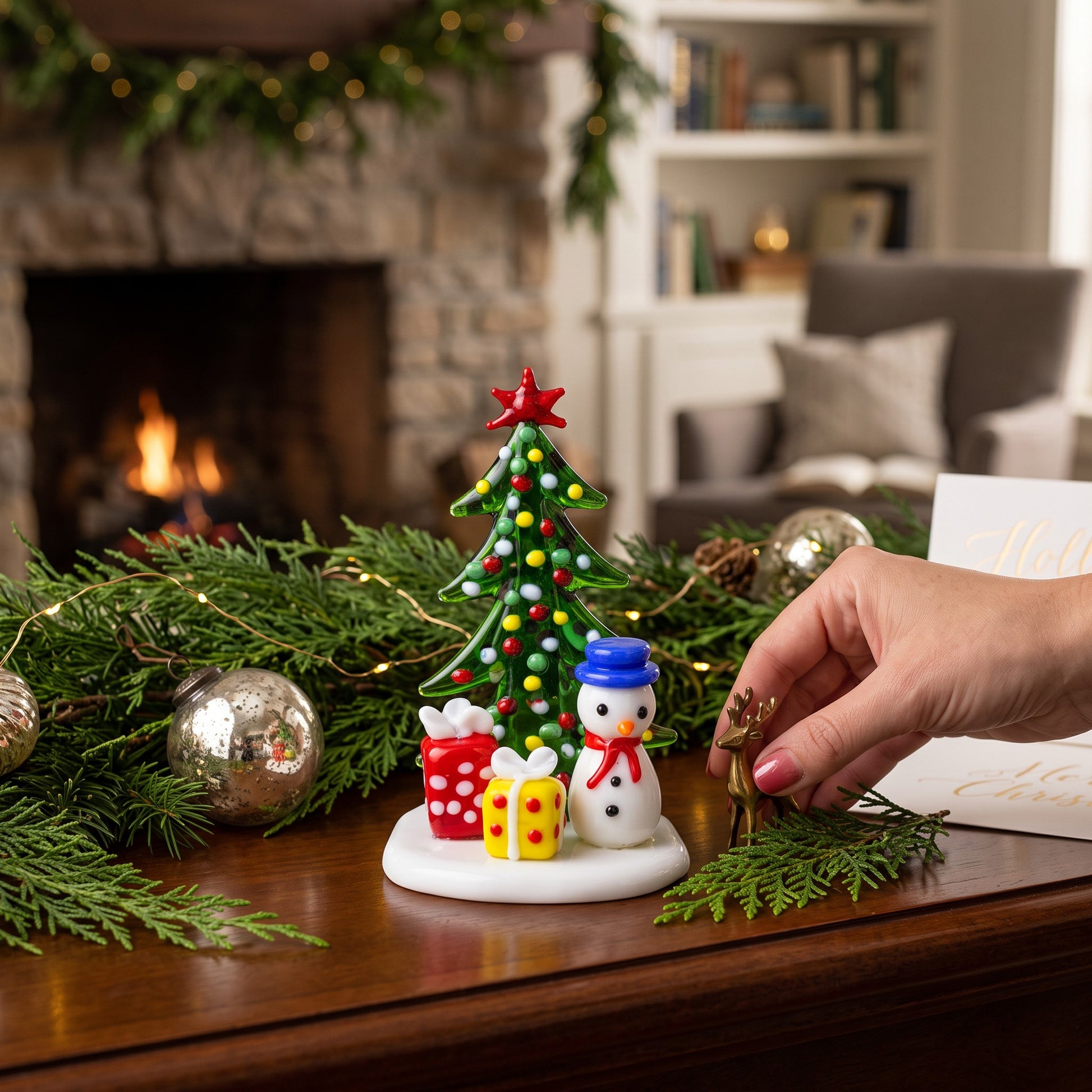 Mellow Monkey Milano art glass Christmas tree figurine with a snowman and gifts on a festive holiday table setting.