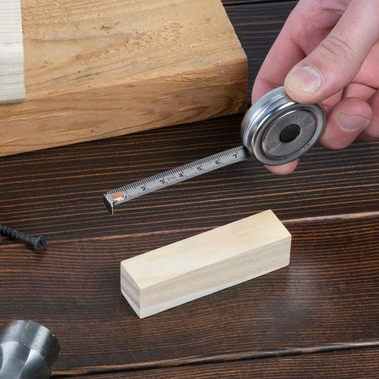 Mellow Monkey mini stainless steel retractable tape measure showing inches and centimeters on a wooden workbench