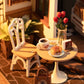 Mellow Monkey Slow Life Café DIY miniature house kit featuring a tiny bistro table, chair, croissant, and coffee cup.