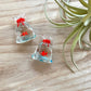 Mellow Monkey miniature glass fish inside a clear glass bag with a red tie, measuring one inch.