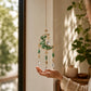 Mellow Monkey moon-shaped suncatcher with green healing stones, gold chains, and hanging crystals in a sunny window.