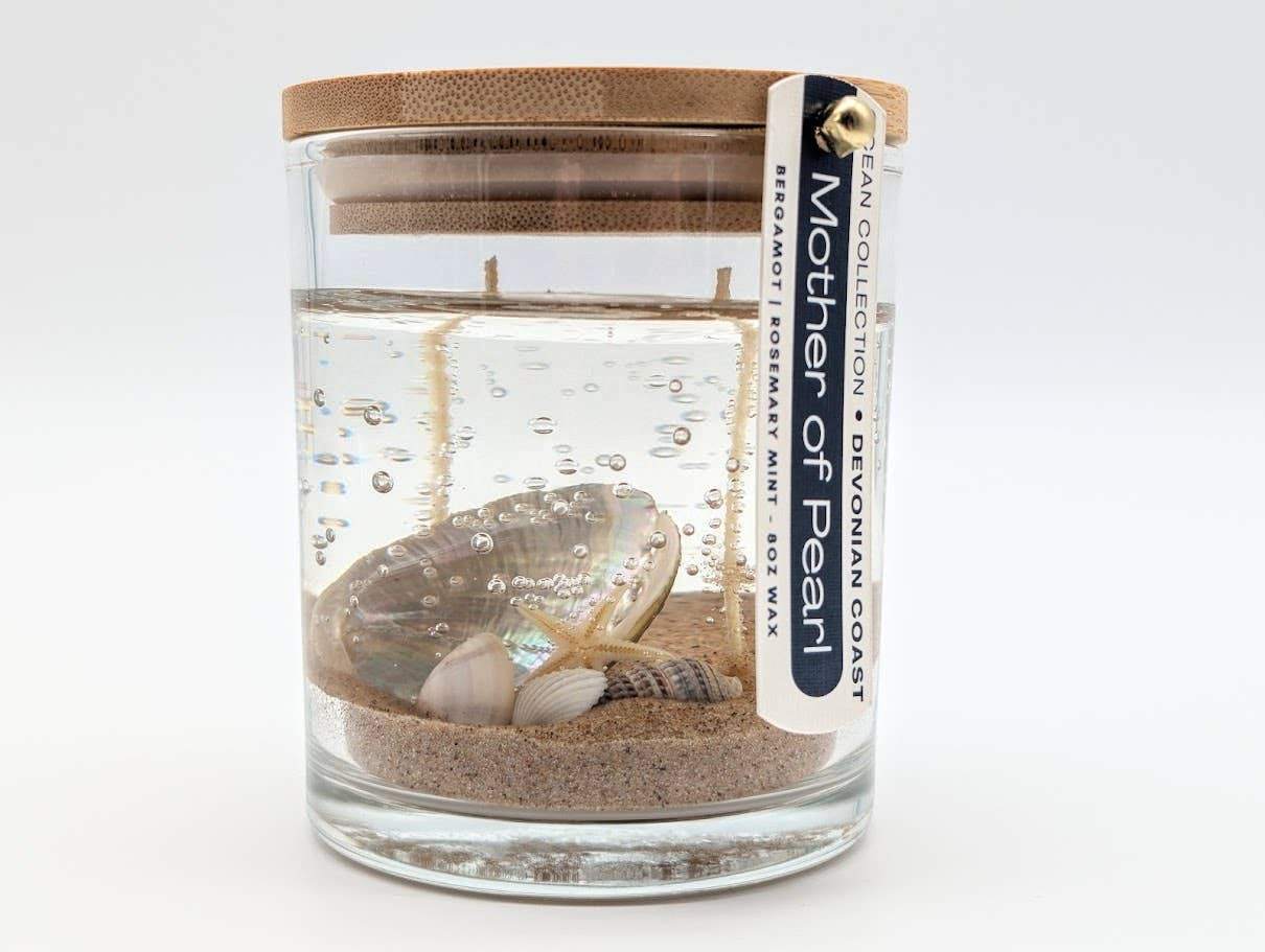 Mellow Monkey Mother of Pearl gel candle with seashells and driftwood scent in a glass jar with a bamboo lid.