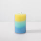 Mellow Monkey multi-scented pillar candle featuring yellow, teal, and blue wax layers with a cotton wick.