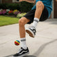 Mellow Monkey multicolored hand-crocheted hacky sack being kicked by a person wearing sneakers and white socks