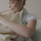 Mellow Monkey Snuggle Me natural organic cotton muslin nursing cover with built-in silicone teether on a mother
