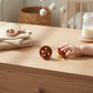 Mellow Monkey eco-friendly natural rubber pacifiers in terracotta brown for babies aged 0-6 months on a wooden table.