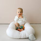 Mellow Monkey baby sitting in a white lounger holding a natural rubber Ember + Ember pacifier