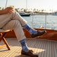 Mellow Monkey heather blue novelty socks with anchor graphic and I'm The Friend With The Boat text worn on a boat deck