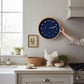 Mellow Monkey navy blue wood marine lunar phase clock with white hands and beech frame, 10-in diameter.