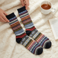 Mellow Monkey navy multi-colored patterned crew socks with a cozy fair isle design on a soft white blanket