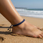 Mellow Monkey navy blue woven cotton nautical anklet worn on a person's ankle at the beach.