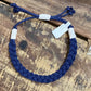 Mellow Monkey navy blue woven cotton nautical anklet with adjustable white cord knots on a rustic wooden surface