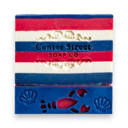 Mellow Monkey New Englander handmade soap bar with red, white, and blue stripes and a lobster cutout.