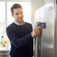 A man in a navy sweater places a Mellow Monkey NBA New York Knicks logo magnet on a stainless steel refrigerator.