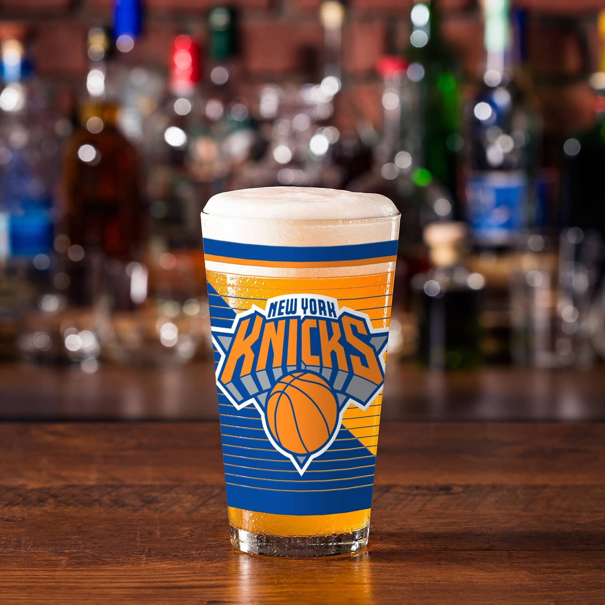 Mellow Monkey 16 oz New York Knicks pint glass with team logo on a wooden bar counter