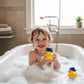 A happy toddler playing in a bubble bath with Mellow Monkey NBA New York Knicks rubber ducks wearing team caps.