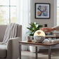 Mellow Monkey New York Knicks sunrise alarm clock with digital display on a wooden side table in a bright living room.