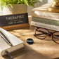 Mellow Monkey 1.25 inch round black pin-back button with white Nope! text on a wooden desk with books and glasses.