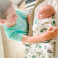 Mellow Monkey NYC themed muslin swaddle blanket wrapped around a baby while an older brother looks on lovingly