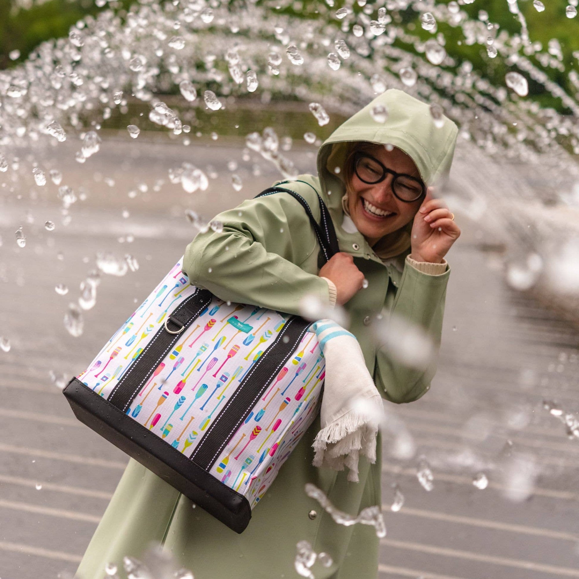 Mellow Monkey Original Deano Small tote bag with colorful oar print, black base, and straps, worn by a smiling woman.