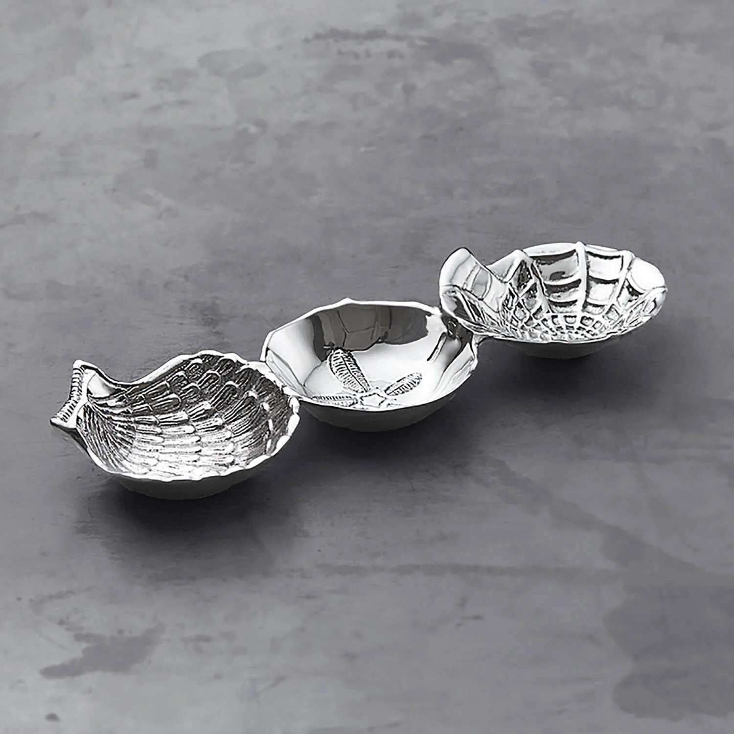 Mellow Monkey OCEAN Shell Triple Dip Tray in silver aluminum, shaped like nautilus, sand dollar, and scallop shells.