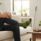Mellow Monkey olive green novelty crew socks with argyle pattern and golfer graphic worn by a person on a sofa