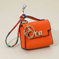Mellow Monkey orange faux leather miniature handbag keychain with colorful scarf detail and gold clasp.